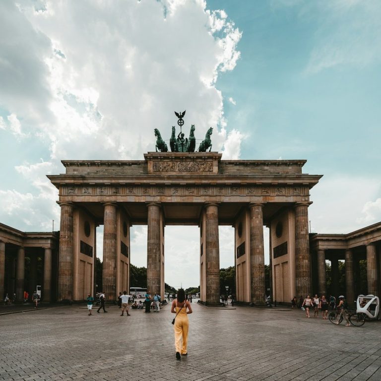Das Brandenburger Tor mit Leuten im Vordergrund und einem bewölkten Himmel.