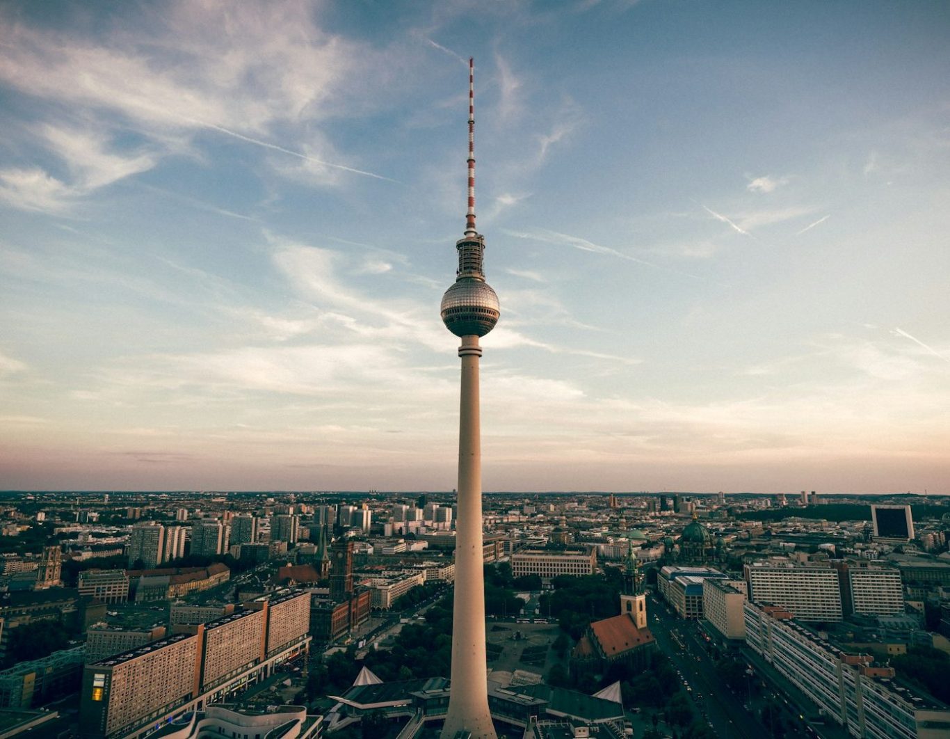 Berliner Fernsehturm vor einem bunten Abendhimmel über der Stadt.